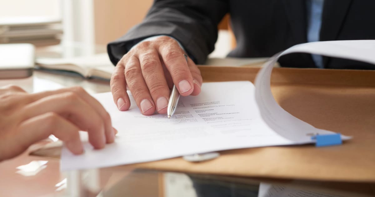 Main pointant section certification CE sur document de conformité menuiserie en français posé sur bureau avec ordinateur portable et échantillon PVC en arrière-plan